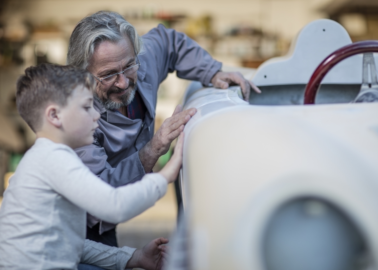 Senior man and boy examining old car together